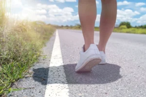 Frau, die auf einer Landstraße mit blauem Himmel im Hintergrund läuft, symbolisiert einen Neuanfang, Fortschritt und den persönlichen Weg.