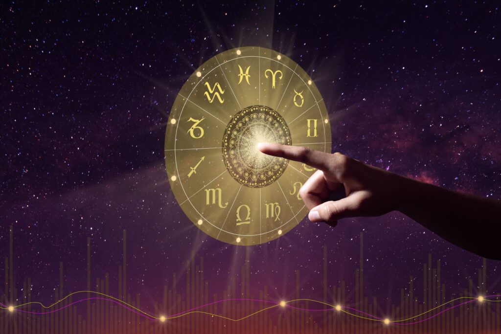 Hand berührt leuchtendes Tierkreisrad vor Sternenhimmel – Symbol für astrologische Ausrichtung und bewusste Entscheidung