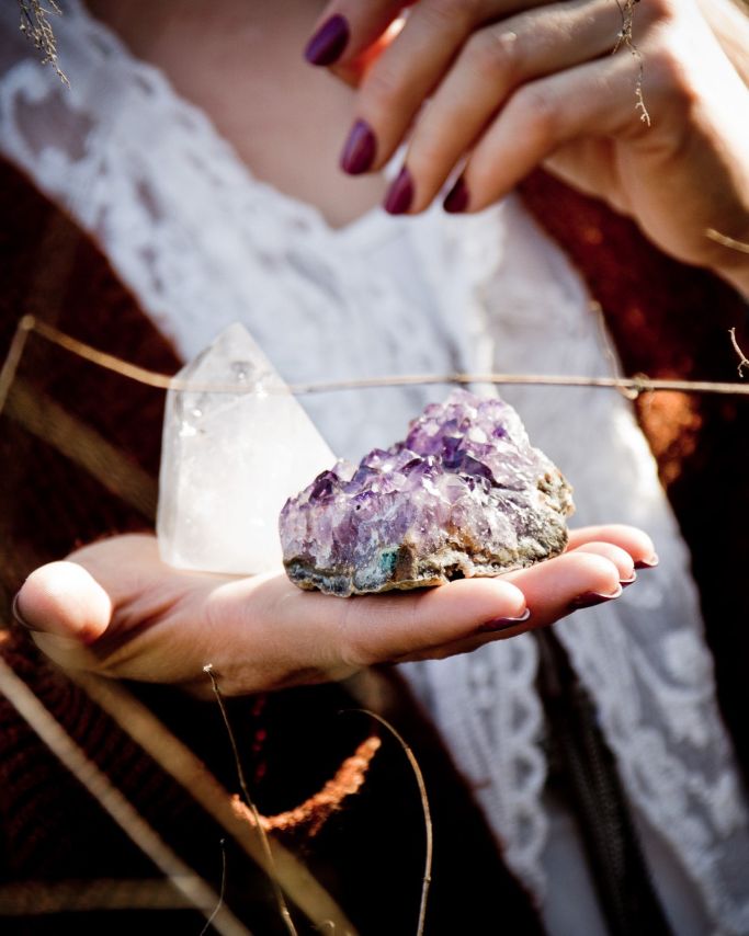 Hand hält Amethyst und Bergkristall in der Natur – Symbol für Energie, Klarheit und spirituelle Verbindung